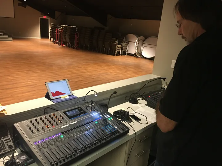 A service technician troubleshooting rack-mounted audio equipment